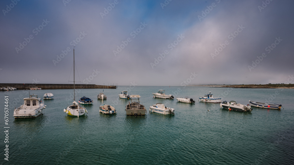 Fototapeta premium A small harbour on the west coast of France with ships at anchor on a foggy day.