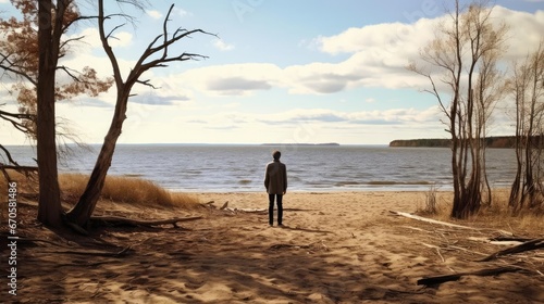 A man on the shore of a lake or the sea looks longingly into the distance © cherezoff