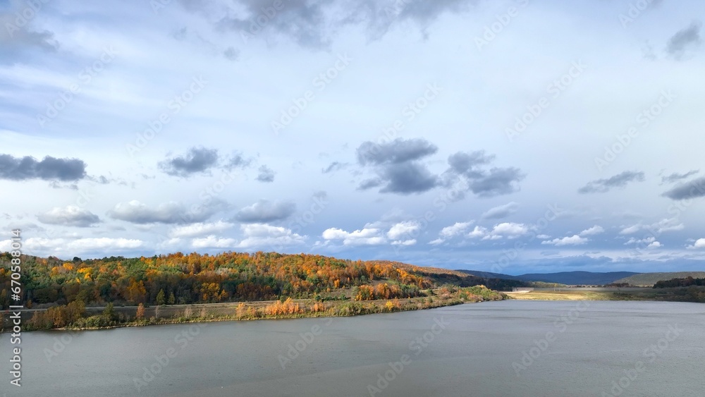 Autumn Fall season sky over hillside with trees by lake in Pennsylvania