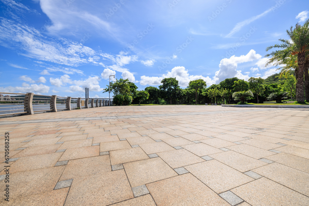 Empty square floor and green forest under blue sky