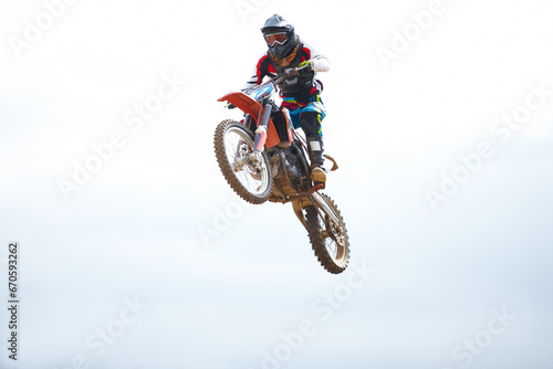 Blue sky, sports and man biker jumping for stunt at competition, race or training for skill. Fitness, active and male athlete on a motorcycle for energy, adrenaline or adventure with speed in nature.
