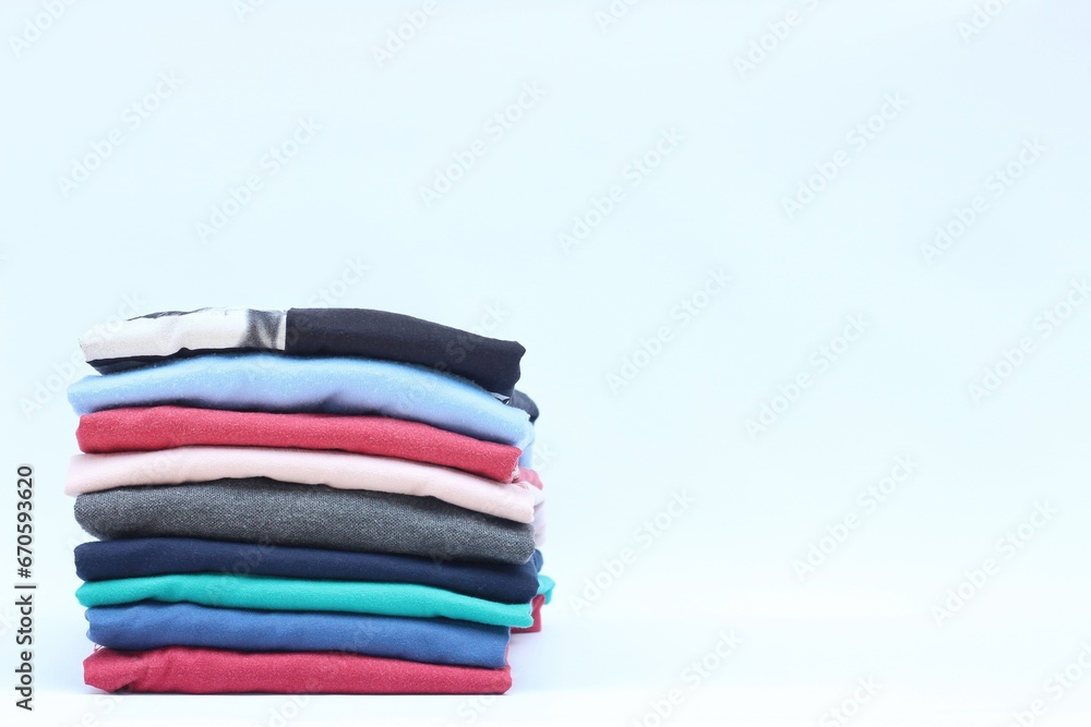 Collection of colorful plain t-shirts is stacked on the table. isolated on white background Collection of colorful plain t-shirts is stacked on the table. isolated on white background