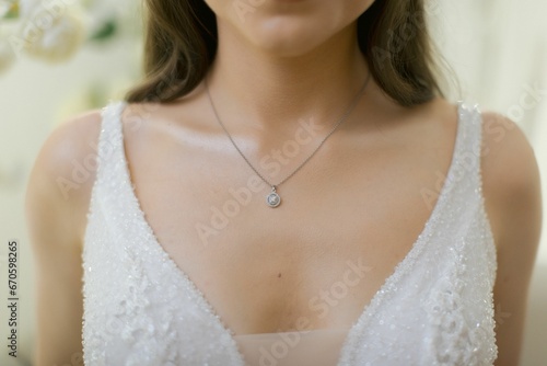 Beautiful woman wearing a white bridal gown with a delicate necklace