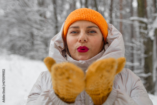 Portrait of happy beautiful girl, young joyful positive woman walking playing with snow, snowflakes, having fun outdoors in winter clothes, hat, smiling. Winter season, weather. High quality photo