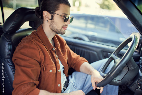 appealing young man in stylish vibrant outfit posing in profile in car while at steering wheel © LIGHTFIELD STUDIOS