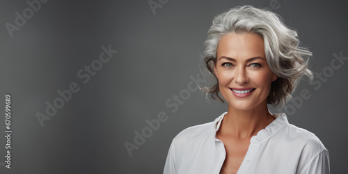 A beautiful middle-aged woman with gray hair and healthy skin is smiling in a good mood. 