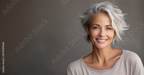 A beautiful middle-aged woman with gray hair and healthy skin is smiling in a good mood.  photo