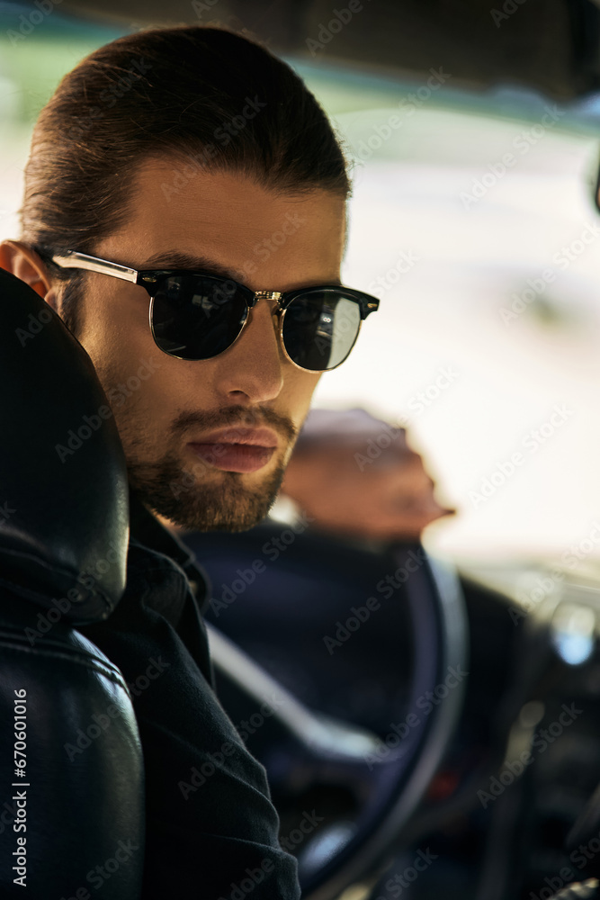 vertical shot of appealing young man with sunglasses behind steering wheel and looking at camera vertical shot of appealing young man with sunglasses behind steering wheel and looking at camera