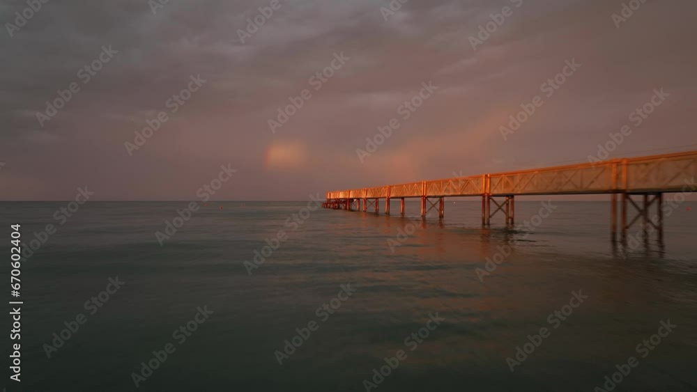 pontile al tramonto sul mare e sullo sfondo l'arcobaleno, visione in movimento con il drone pontile al tramonto sul mare e sullo sfondo l'arcobaleno, visione in movimento con il drone