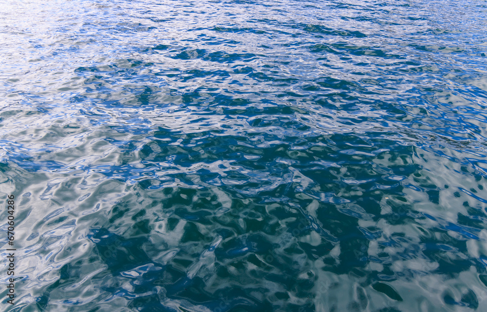 Obraz premium Small ripples reflect morning sun on calm ocean water