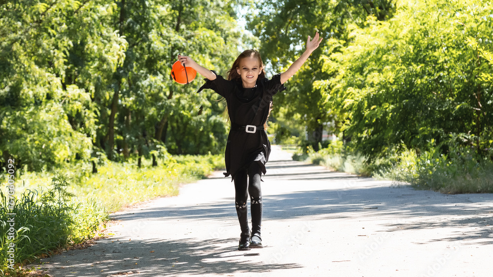 Fototapeta premium Happy Halloween. Cute little witch with a pumpkin in the hands.