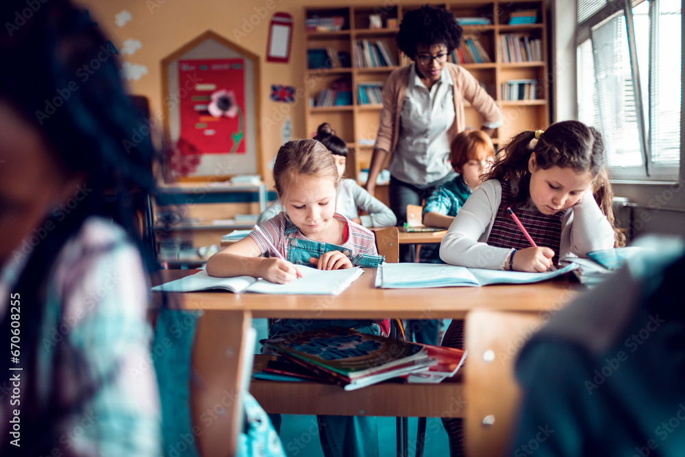 Two young girls diligently working on their assignments in class Two young girls diligently working on their assignments in class