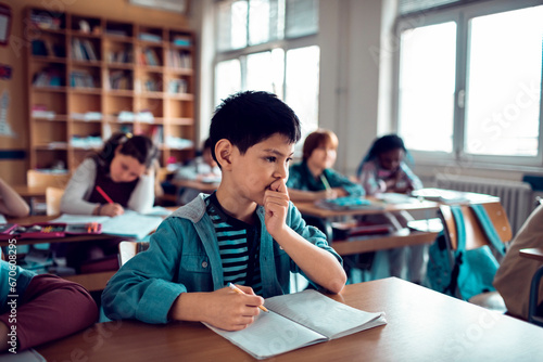 Thoughtful young boy in a classroom setting photo