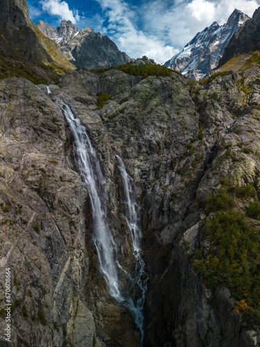 Breathtaking landscape featuring a majestic waterfall cascading down a rocky outcrop on Mount Ushba