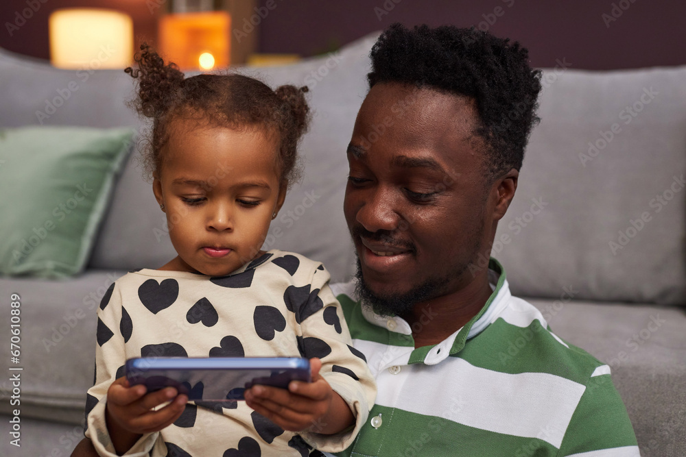 Portrait of young Black father and daughter using smartphone together for supervised screen time - obrazy, fototapety, plakaty 