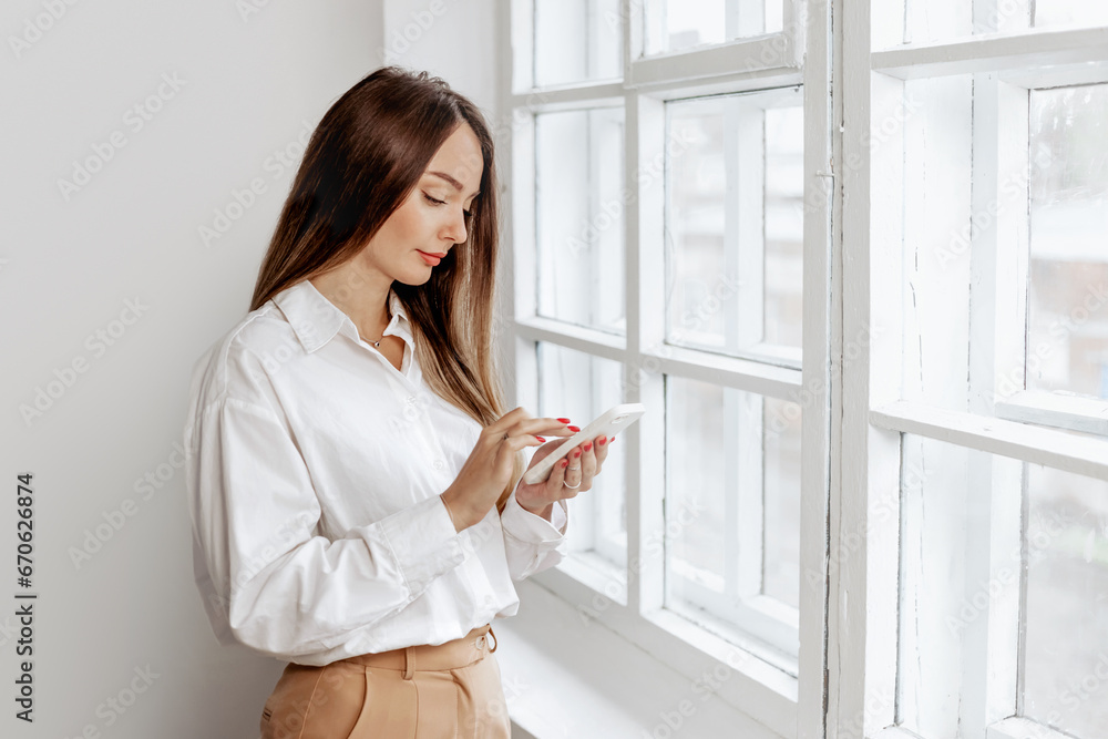 Smiling caucasian businesswoman with smartphone looking at screen during work at office