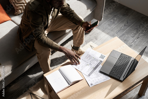 Canvas Print High angle portrait of Black adult man doing taxes at home in sunlight with fina