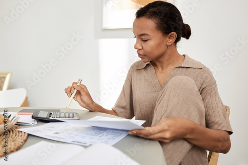 Canvas-taulu Minimal side view portrait of young Black woman doing taxes at home and using ca