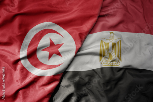 big waving national colorful flag of tunisia and national flag of egypt .