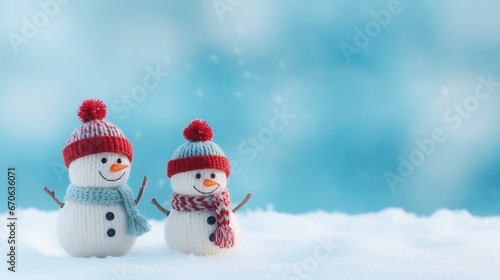 Christmas wallpaper of two little knitted snowmen with on soft snow on blue background