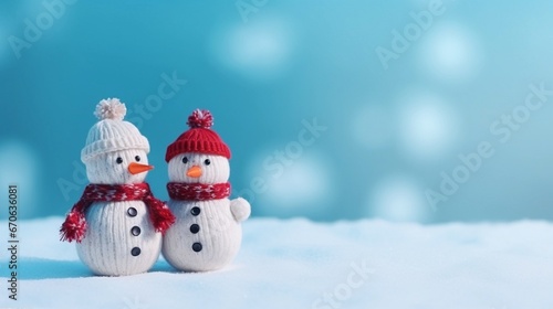 Christmas wallpaper of two little knitted snowmen with red scarf on soft snow on blue background © C R