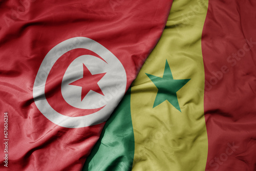 big waving national colorful flag of tunisia and national flag of senegal .