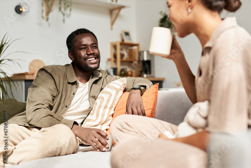Portrait of young African American couple talking joyfully in morning in cozy home, everyday life