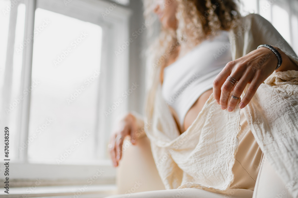 Obraz premium Partial view of blurred woman touching crochet cover-up near window in studio 