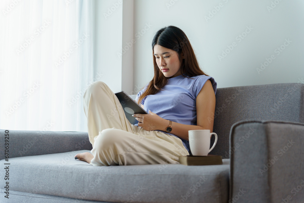 Woman holding a book device reading on e-book on digital tablet device or social media apps online ecommerce Woman holding a book device reading on e-book on digital tablet device or social media apps online ecommerce