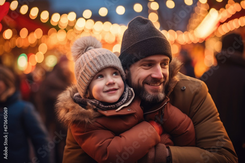 Father and child having god time on traditional Christmas market on winter evening in town decorated with lights