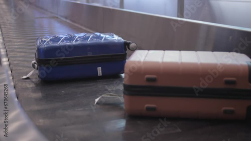 Two plastic suitcases move on the airport baggage belt. Unclaimed suitcases left on the baggage belt.