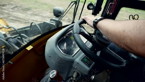 tractor driver sitting inside vehicle, closeup view of male hand on steering wheel