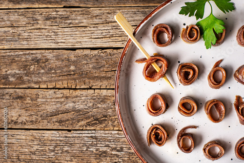 Cantabrian anchovies rolled and presented on a rustic plate, on an old wooden table, top view. Copy space. photo