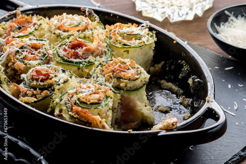 An appetizer of zucchini roll ups topped with parmesan cheese