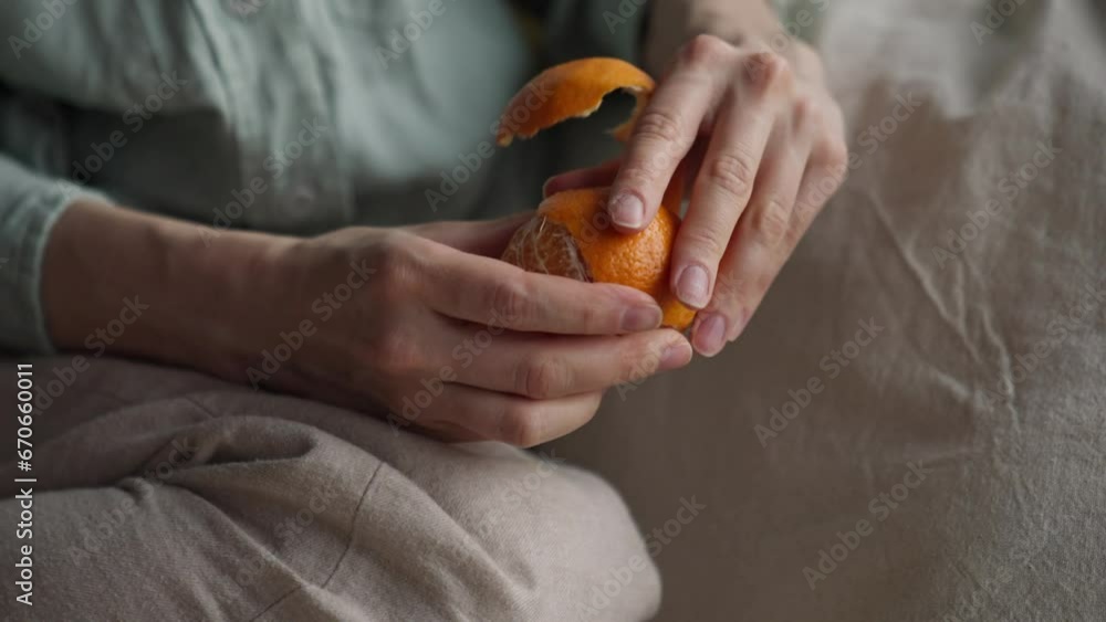 Close up lady hands claen orange mandarin relax sitting on pillow on the floor near the window in a rainy day. Close up lady hands claen orange mandarin relax sitting on pillow on the floor near the window in a rainy day.