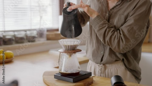Morning coffee brew with kettle pouring hot water in chemex, v60 origami paper filter. Concept of alternative coffee at home