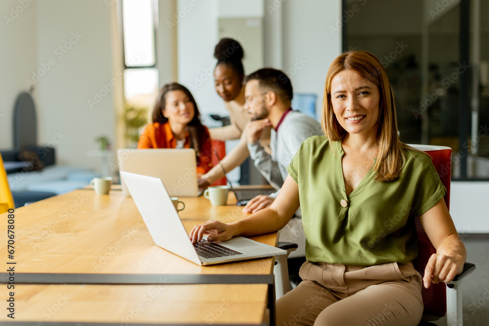 Business woman working on laptop with her young multiethnic startup team working in the modern office Business woman working on laptop with her young multiethnic startup team working in the modern office