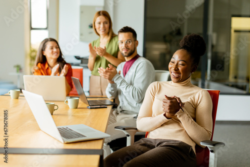 Cute Africam American woman with her young multiethnic startup team working in the modern office