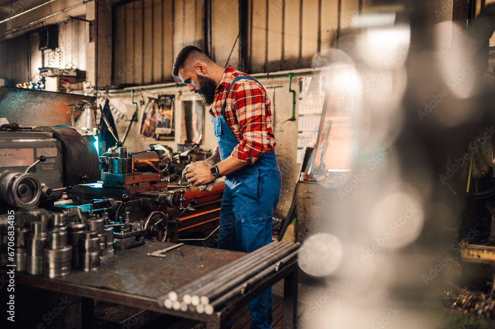 A mechanic cleaning hands with a cloth in front of a machine with various parts on the table. A mechanic cleaning hands with a cloth in front of a machine with various parts on the table.