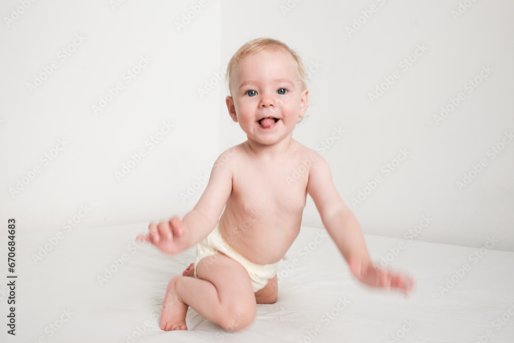 Happy baby in panties is playing on white bed in white room Happy baby in panties is playing on white bed in white room