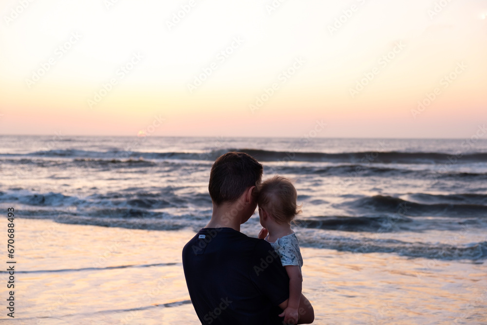silhouettes of father and baby on sunrise ocean background,family concept silhouettes of father and baby on sunrise ocean background,family concept