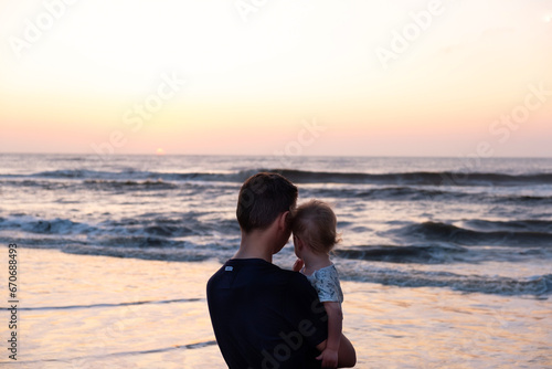 silhouettes of father and baby on sunrise ocean background,family concept