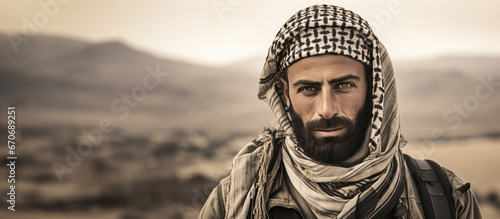 Portrait of an Arab man looking at the camera covered with a traditional black and white Arabic scarf.