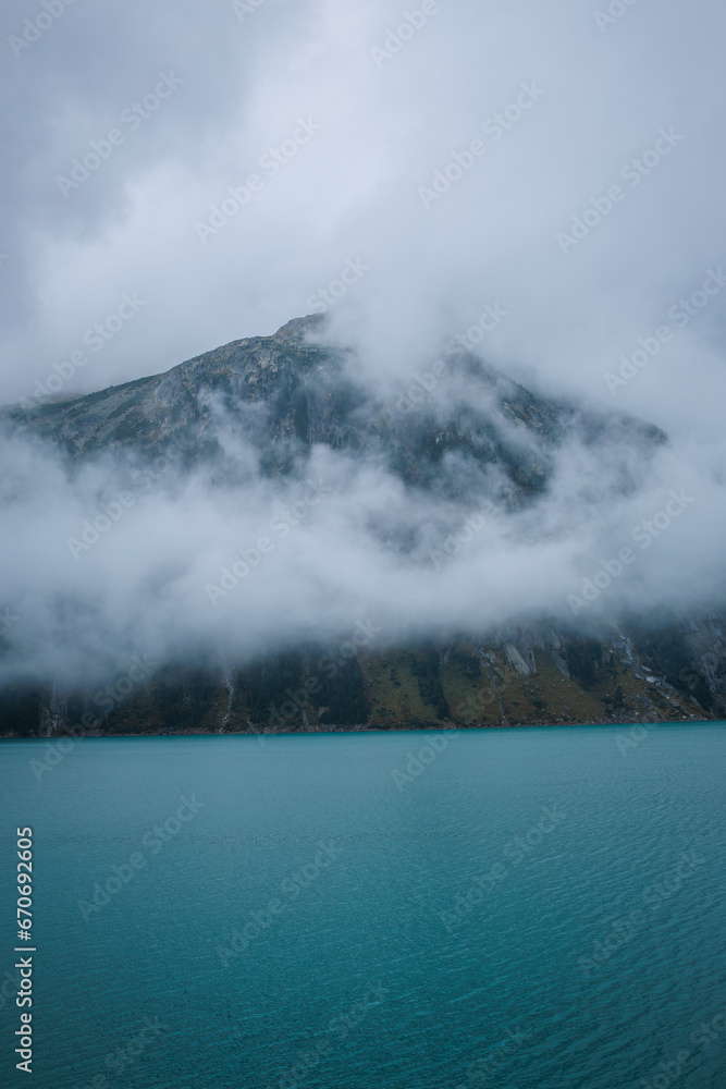 Fototapeta premium Nestled serenely amidst the rugged peaks of the majestic mountains, this pristine alpine lake captivates with its breathtaking beauty.