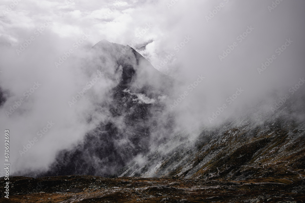 
The mountains, shrouded in a delicate veil of clouds, create an ethereal and mysterious landscape.
