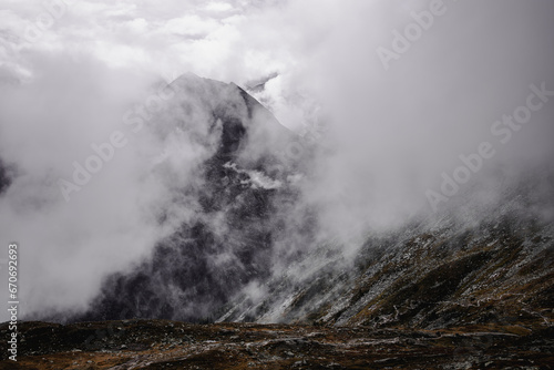  The mountains, shrouded in a delicate veil of clouds, create an ethereal and mysterious landscape.