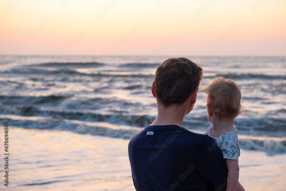 silhouettes of father and baby on sunrise ocean background,family concept silhouettes of father and baby on sunrise ocean background,family concept