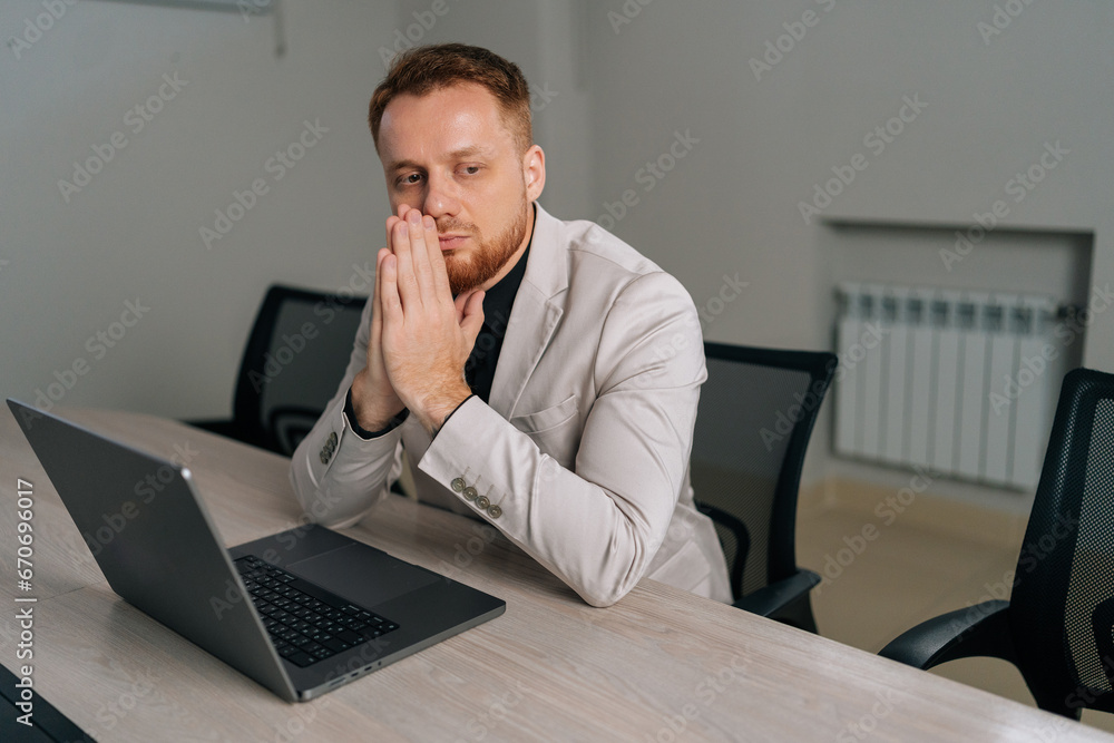 Portrait of thoughtful business man in suit sitting at desk with clasped palms thinking search problem solution, collect thoughts together, organize emotional state before important meeting. Portrait of thoughtful business man in suit sitting at desk with clasped palms thinking search problem solution, collect thoughts together, organize emotional state before important meeting.
