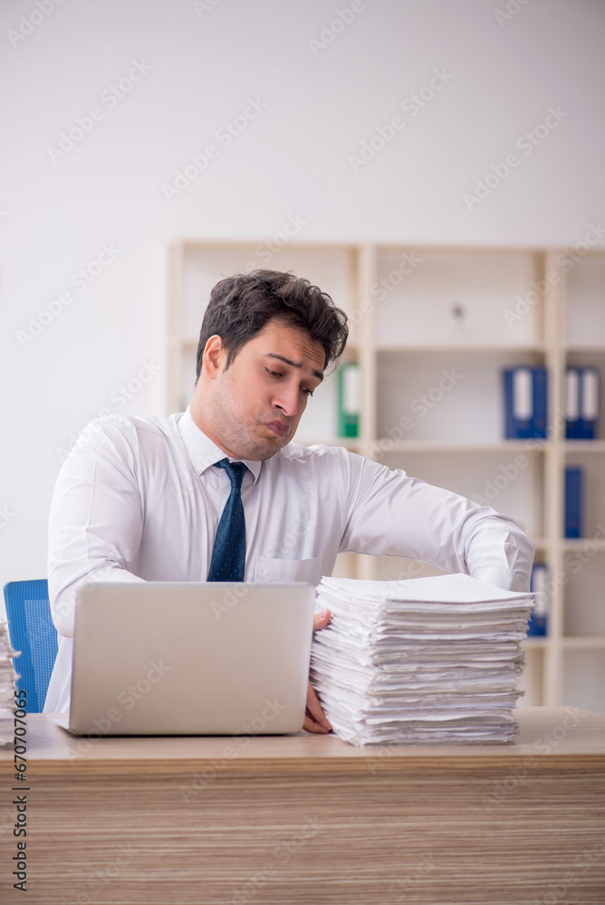 Young male employee and too much work in the office Young male employee and too much work in the office
