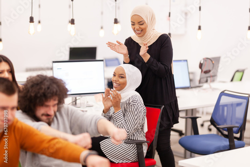 Two african american muslim girls with hijab applauding. Colleagues cheering together in a modern office